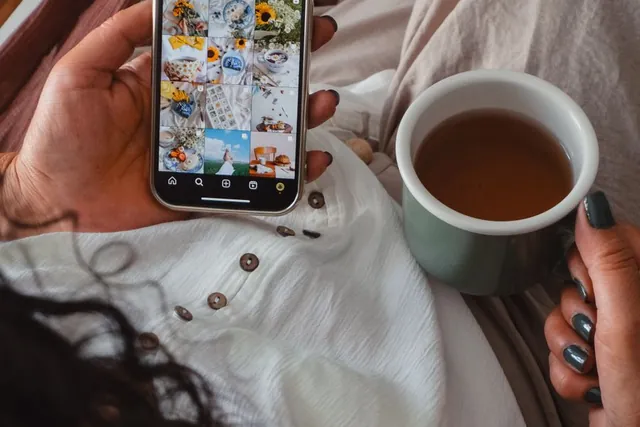 Hands holding a cup of tea and a phone