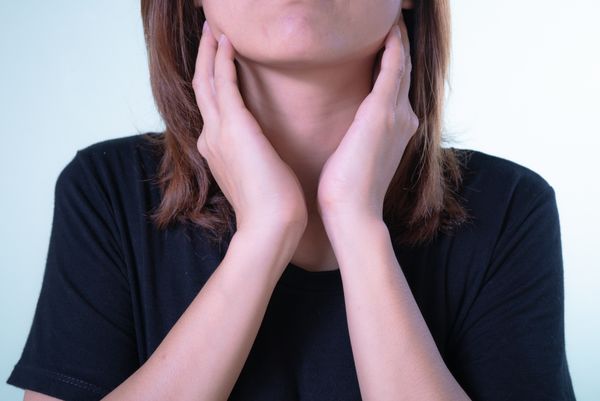 A woman with her hands at her neck