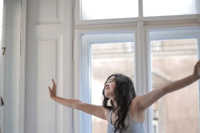 A woman stretching by a bright window