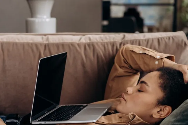 A woman asleep on the sofa beside her laptop